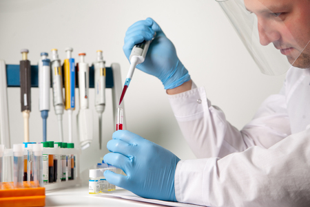 Scientific laboratory technician working with blood and biomaterial via sampler metering and other laboratory equipment in the laboratoryの写真素材