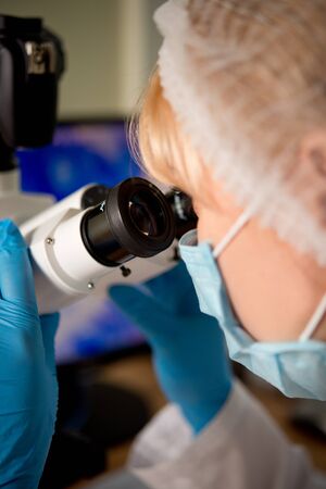 Laboratory assistant or technician in medical research lab looking into a microscope and doing researchの写真素材