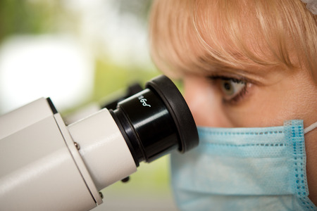 Laboratory assistant or technician in medical research lab looking into a microscope and doing researchの写真素材