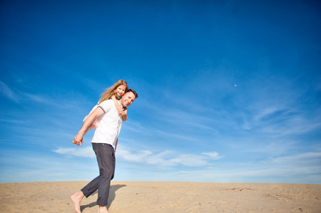 Dad and little girl daughter playing on the beach, fly, run, laugh at the blue sky backgroundの写真素材