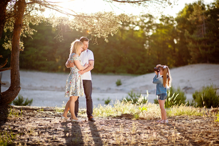 Happy family rest on nature, girl photographs her father and motherの写真素材