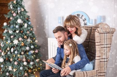 Family of mother, father and little child daughter near Christmas tree with presents, decorations and New Year or Christmasの写真素材