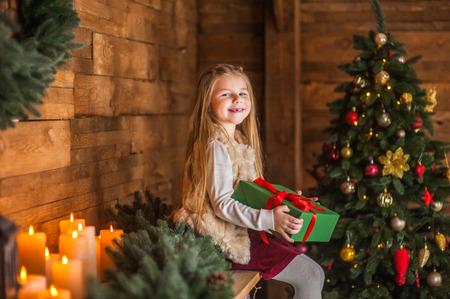 Girl, daughter, smiling, glad opens and 
receives gifts on Christmas Eve or New Year near Christmas treeの写真素材
