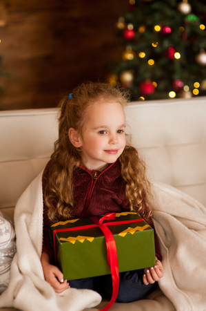 A girl is sitting with a New Year's gift. Christmas Eve or New Year's Eve.の写真素材