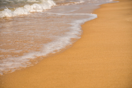 Background. A close-up of a wave runs over a sandy beachの写真素材