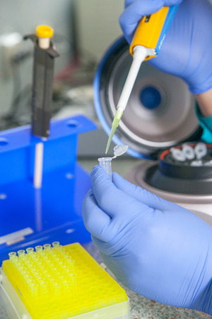 scientist or laboratory technician working with dispenser, a centrifuge, test tubes and other laboratory instrumentsの写真素材