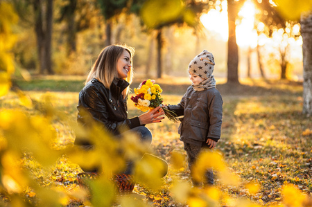 Mom and son with a small child are walking in a autumn forest or park, mother's dayの写真素材