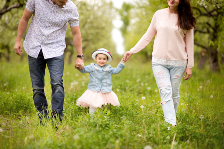 Family mom, dad and daughter are walking in the spring in a flowery garden, happy, laughingの写真素材
