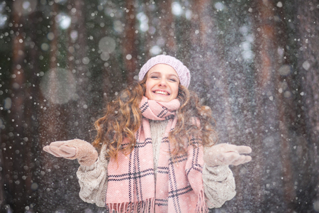 Beautiful girl with long hair man in love catching snowflakes and laughing in winter forest during a snowfall, photos with toningの写真素材