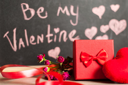 Composition consist of roses, gift boxes and heart near the white sheet with the inscription on...