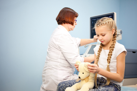 The girl with a soft toy in the hospital on a background of ultrasound machines, smiling and playingの写真素材