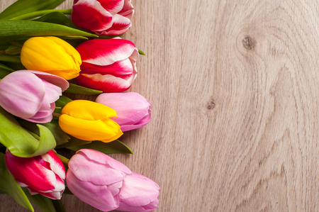 The composition of tulips of different colors on a wooden background, greeting card with free place for inscriptions on Easter or any holidayの写真素材