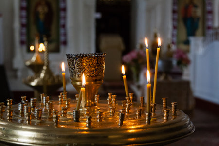 Church candles burn in a candlestick against the backdrop of icons