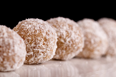 Beautiful sweets with coconut on a white plate on a black background close-up