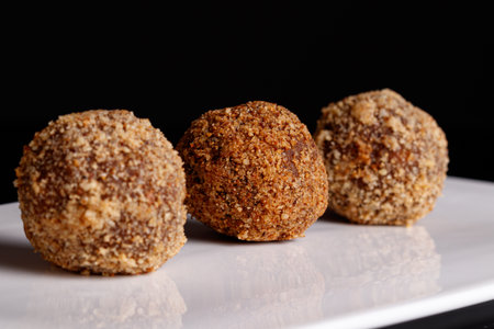 Beautiful candy truffle on a white plate on a black background close up
