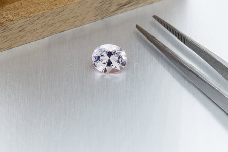 macro mineral faceted stone Morganite with tweezers on a gray background close-up