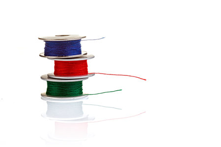 spools of thread in blue, red, green colors on a white background close-up