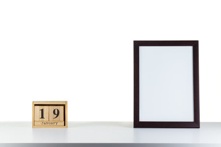 Wooden calendar 19 January with frame for photo on white table and background close-up