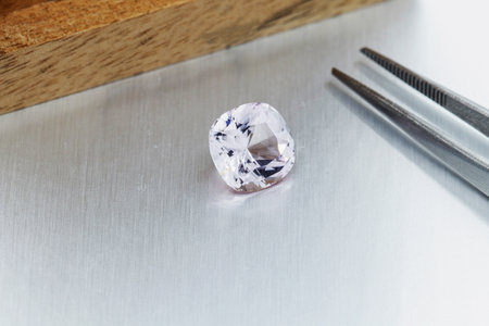 macro mineral faceted stone Morganite with tweezers on a gray background close-upの写真素材