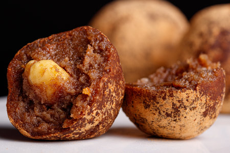 Beautiful candy truffle with a nut inside on a white plate on a black background close-upの写真素材