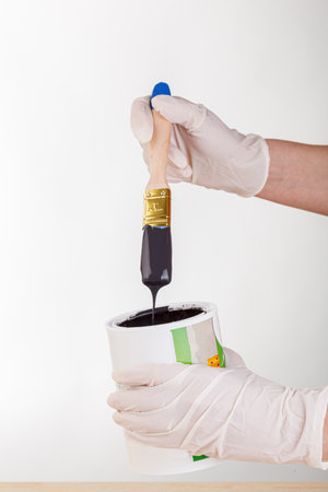 hand with a brush and a can of paint on a white background close-upの写真素材