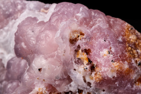 Macro pink Smithsonite mineral stone on microcline on black background close upの写真素材
