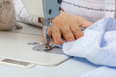 Female hands of a master tailor at work, a sewing machine needle close-upの写真素材