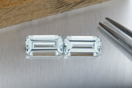macro mineral faceted stone aquamarine with tweezers on a gray background close-up