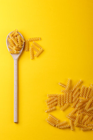 Different types and shapes of dry Italian pasta on a yellow background close-upの写真素材