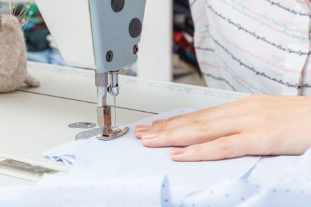 Female hands of a master tailor at work, a sewing machine needle close-upの写真素材
