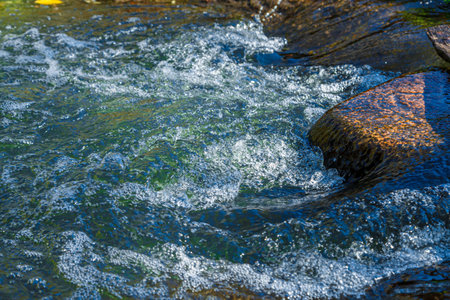 flow of water and spray from a stone close upの写真素材