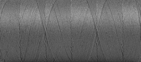 Texture of threads in a spool of gray color on a white background close-up