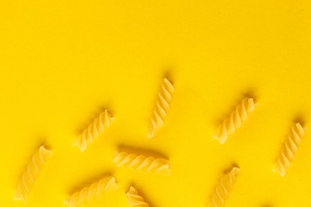 Different types and shapes of dry Italian pasta on a yellow background close-up