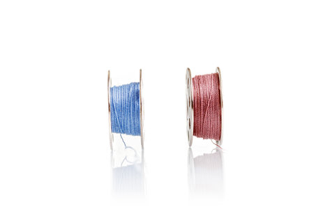 spools of blue and pink thread on a white background close-up