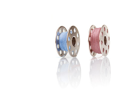 spools of blue and pink thread on a white background close-upの写真素材