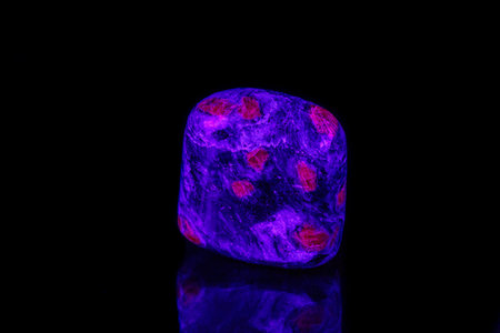 macro mineral stone ruby under ultraviolet light on a black background close-up