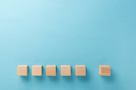 wooden cubes six pieces in a row on a blue background close-upの写真素材