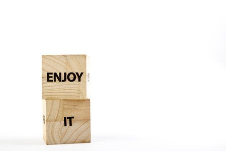 Wooden cubes with the inscription enjoy it on a white background close upの写真素材