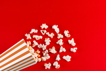 box with popcorn striped in different colors on a red background close-upの写真素材