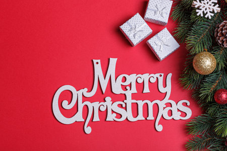 beautiful branches of a Christmas tree with cones and toys on a red background with the inscription Merry Christmas close-upの写真素材