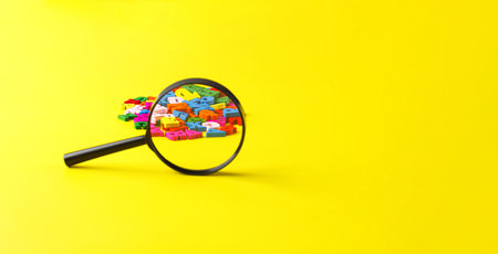 colored letters of the alphabet with a magnifying glass on a yellow background close-upの写真素材