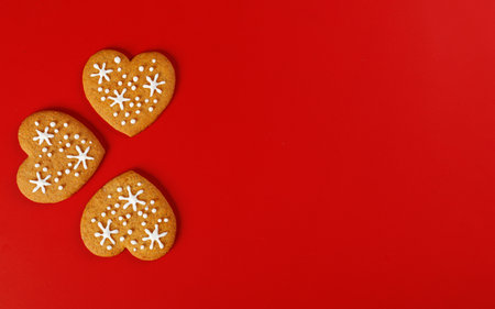 beautiful hand-baked cookies in the shape of a heart on a red background close-upの写真素材