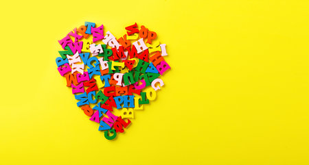 colored letters of the alphabet in the shape of a heart on a yellow background close-up