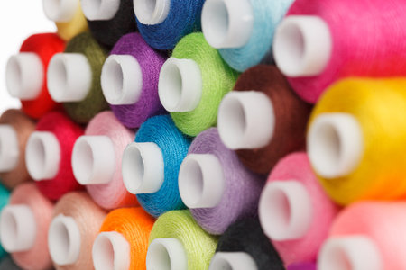 multi-colored spools of sewing thread on a white background close-up