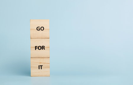 Wooden cubes with inscriptions Go For It on a blue background close-upの写真素材