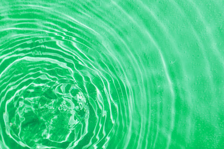drops on water with circles on a green background close upの写真素材