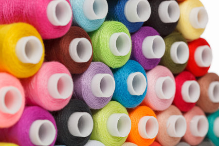 multi-colored spools of sewing thread on a white background close-upの写真素材