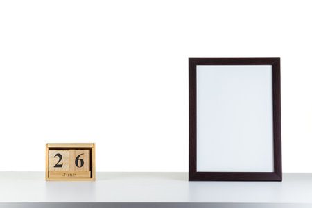 Wooden calendar 26 June with frame for photo on white table and background close-upの写真素材