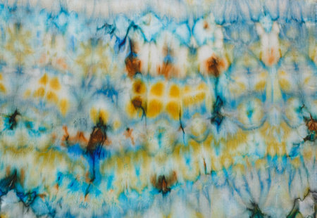 abstract pattern on silk fabric texture in blue, yellow, green colors close upの写真素材