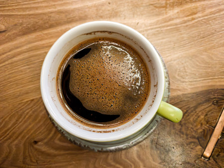 top view of a Green coffee cup on a wooden cafe table with cozy ambiance. Ideal for lifestyle, beverage, and cafe interior themes.の写真素材